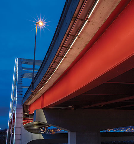 Illuminated by warm white linear LEDs, the red deck girder draws your eye to the bridge’s sweeping silhouette.