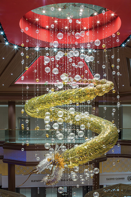 A dragon chandelier stands out with spotlights on its unique details—whiskers, scales and cascading hand-blown spheres.